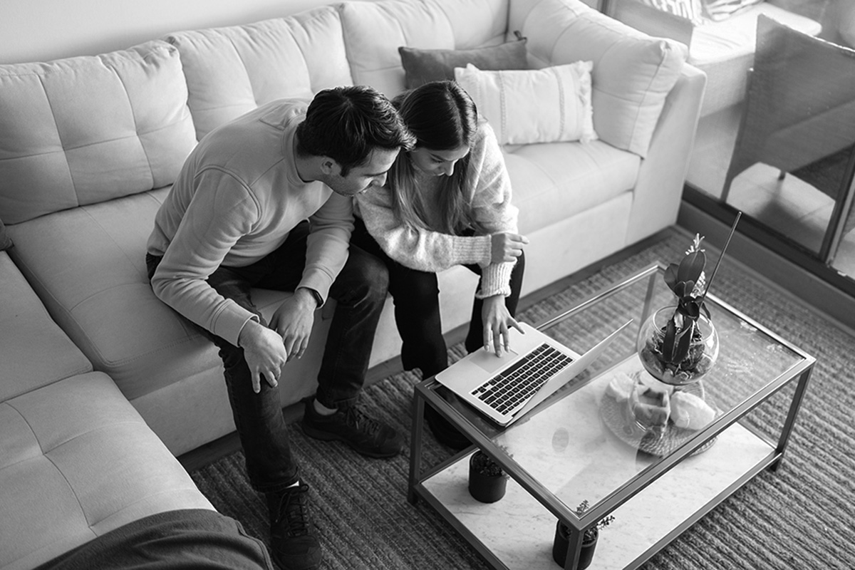 young couple looking at homes on the couch