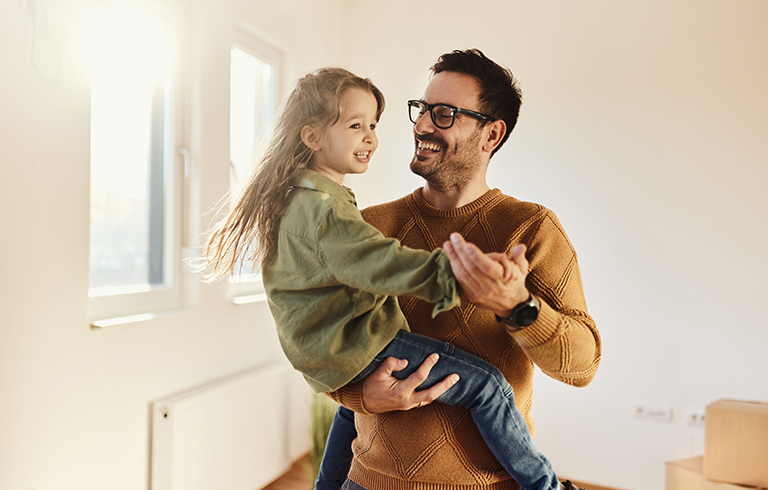 father holding his daughter and smiling