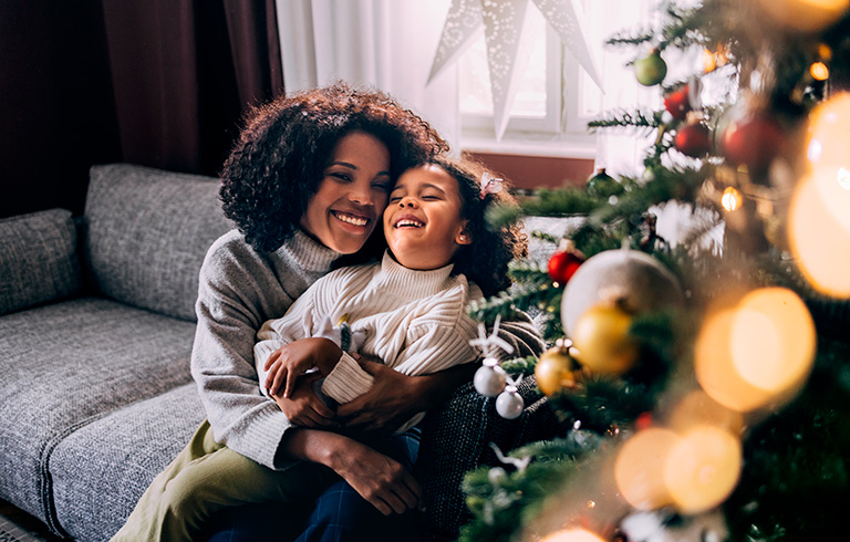 mother and daughter hugging by the christmas tree