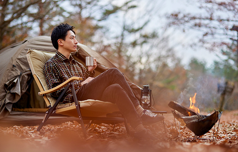 man sitting at a small fire in his campsite