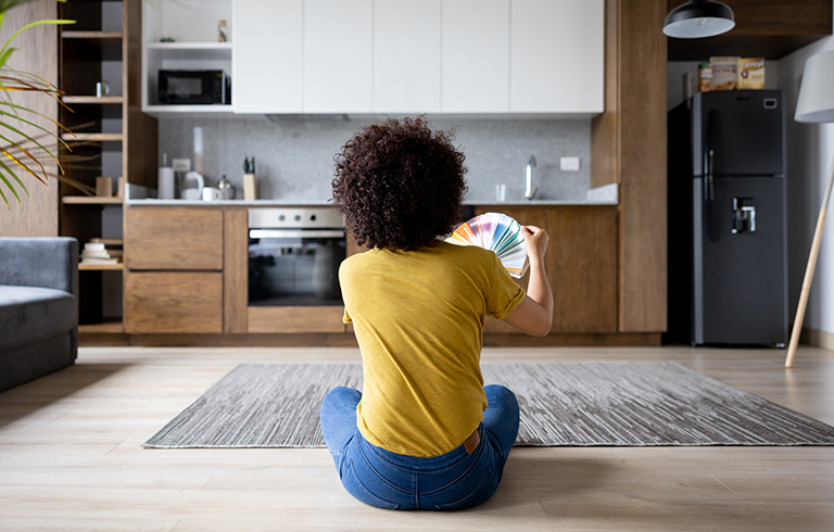 woman sitting on the floor contemplating paint samples