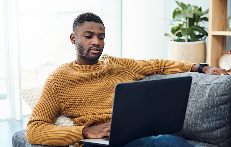 young man sitting on the couch using his laptop