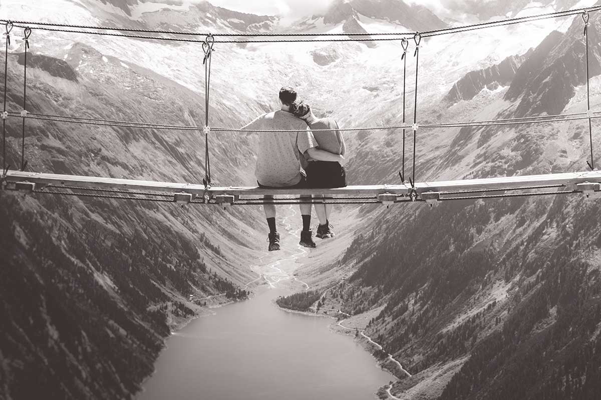 couple sitting on a scenic rope bridge
