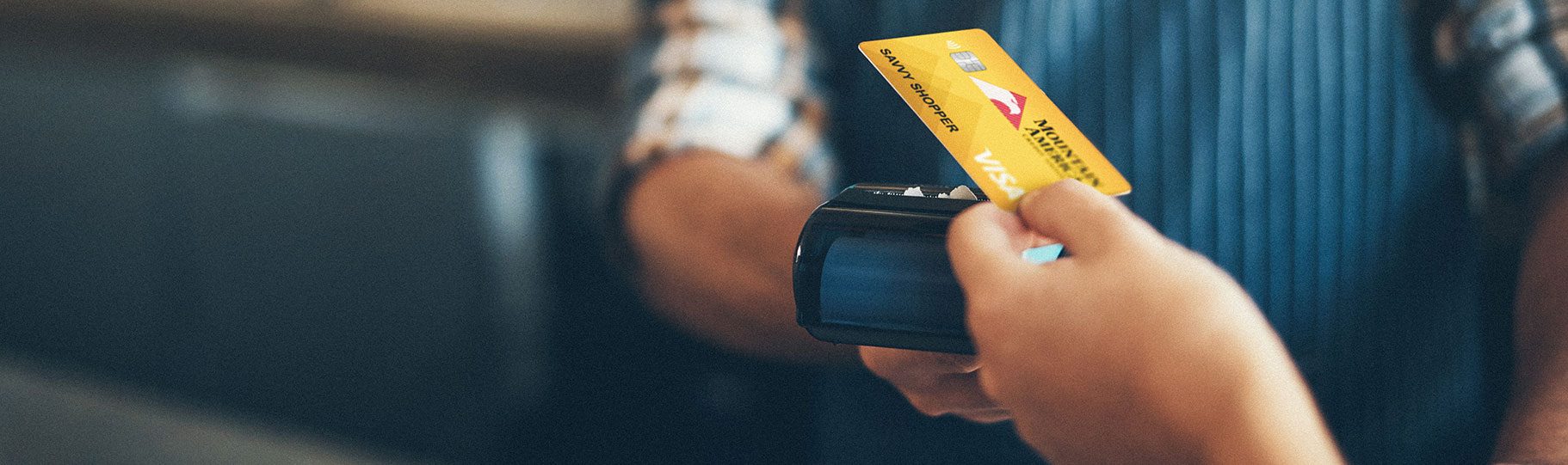 close up of a person tapping a mountain america Visa card on a card reader