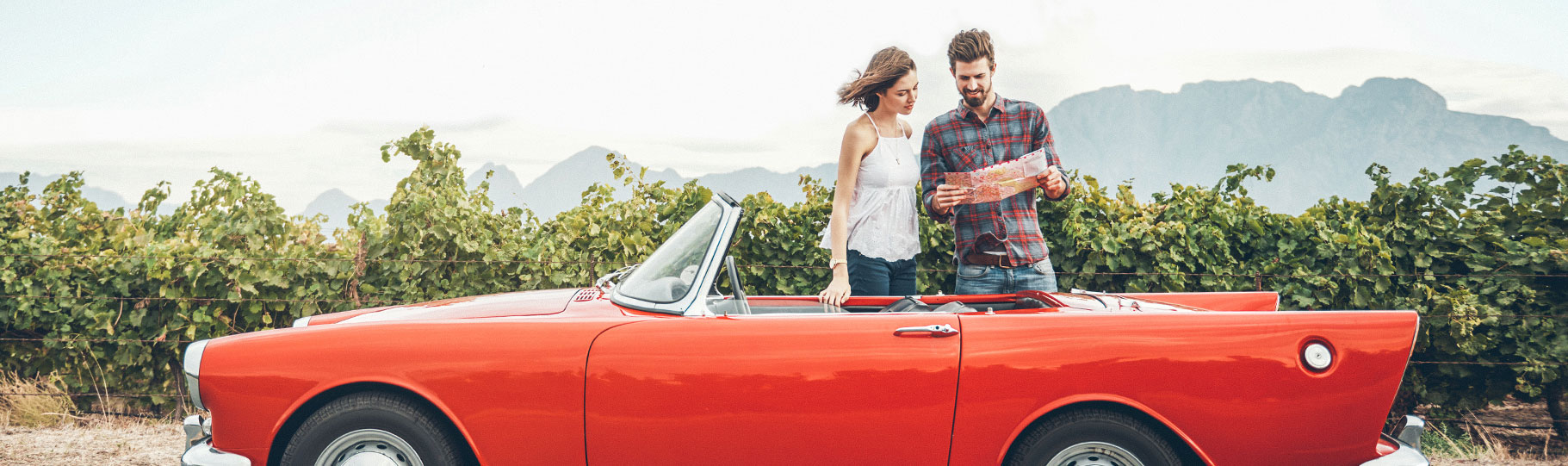 couple looking at a map next to a red car