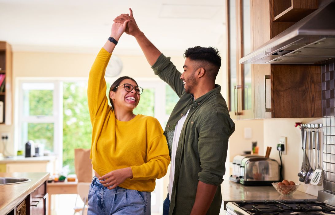 young hispanic couple dancing in the kitchen