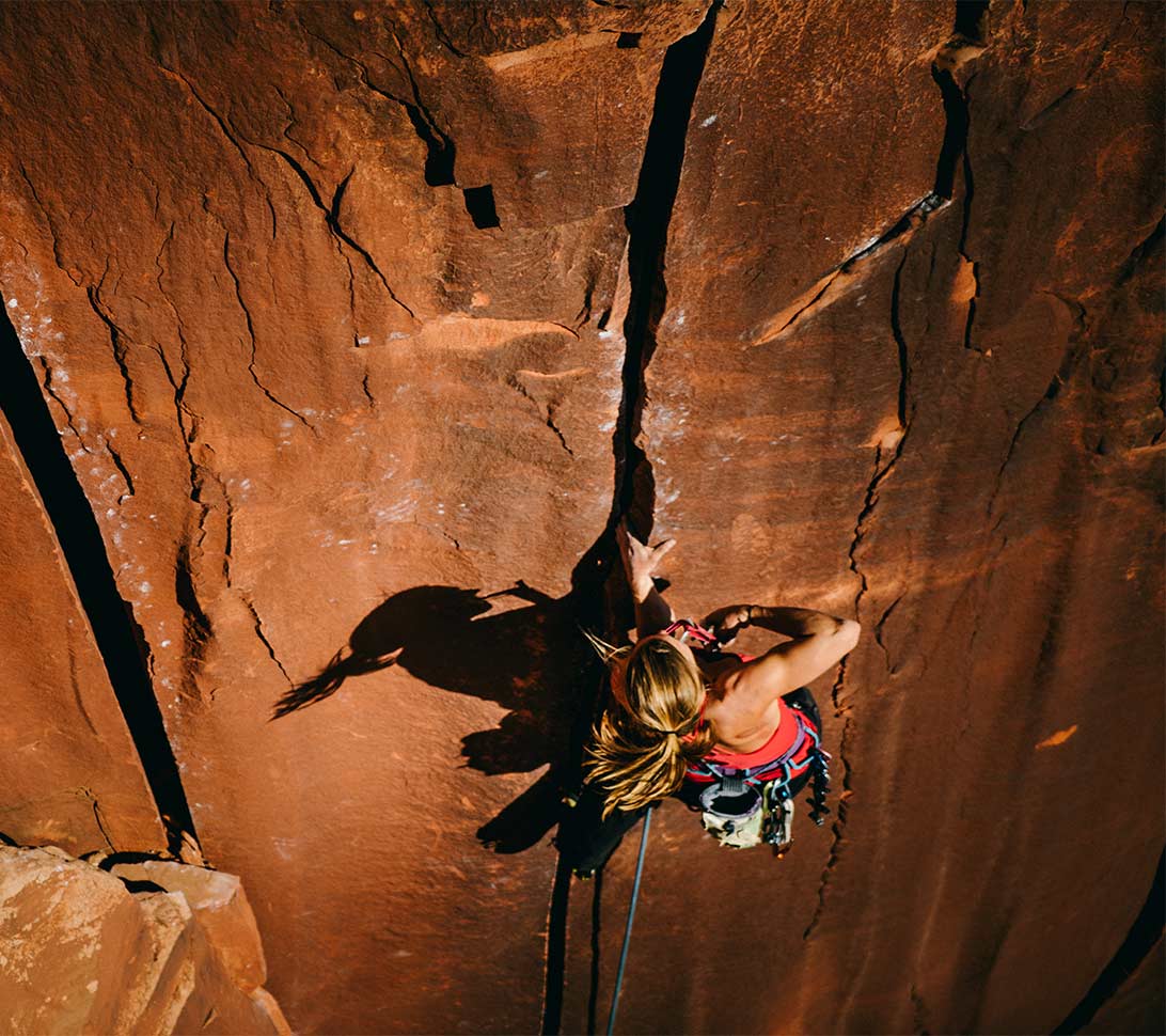 Woman rock climbing on red rock wall