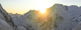Sun rising over snowy mountain peak