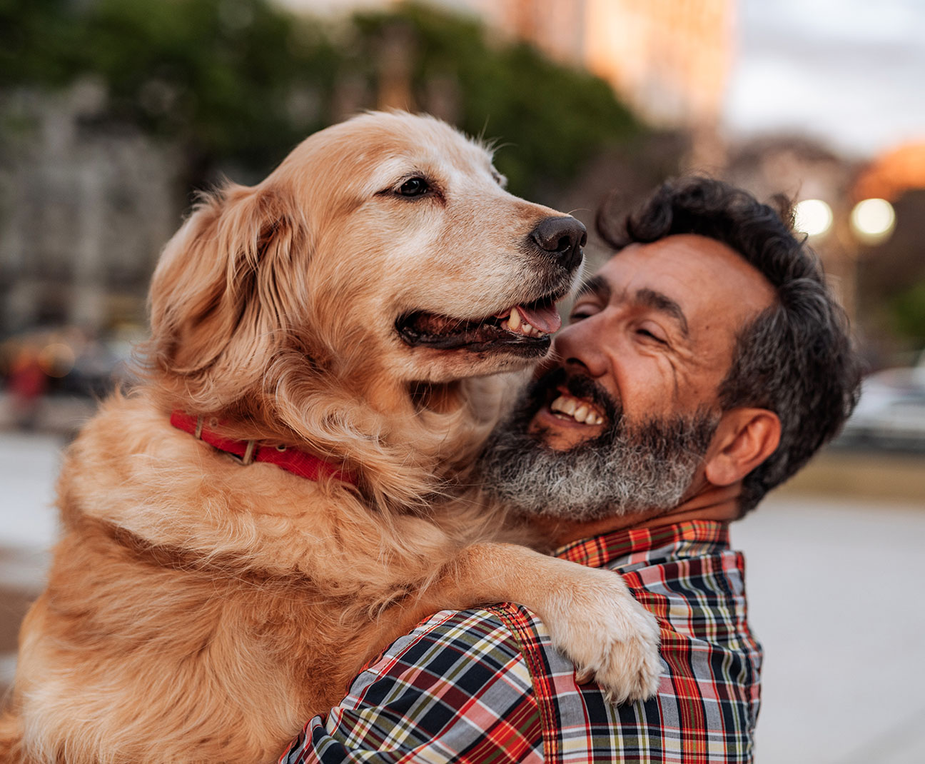 man hugging his golden retriever while smiling