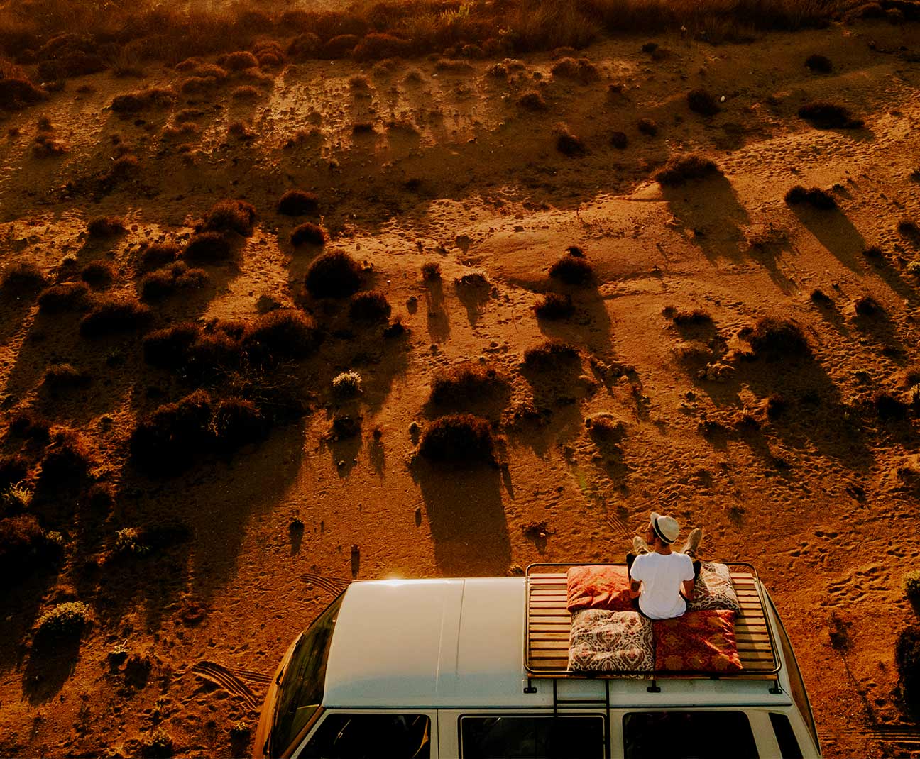 man sitting on van in the desert