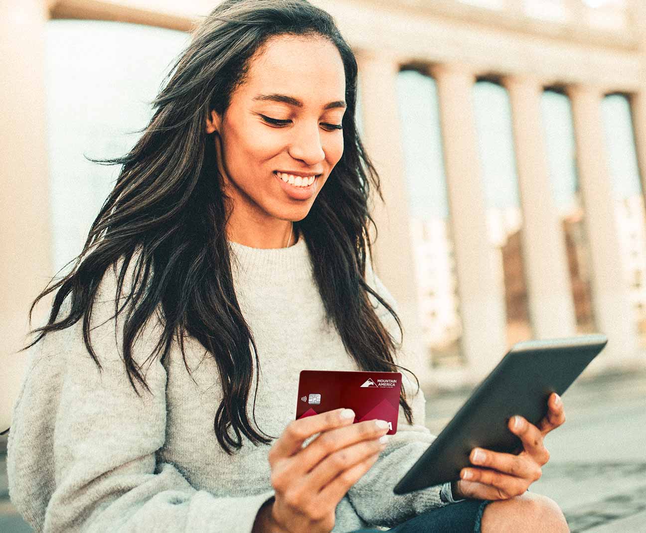 Woman holding a red credit card and tablet computer