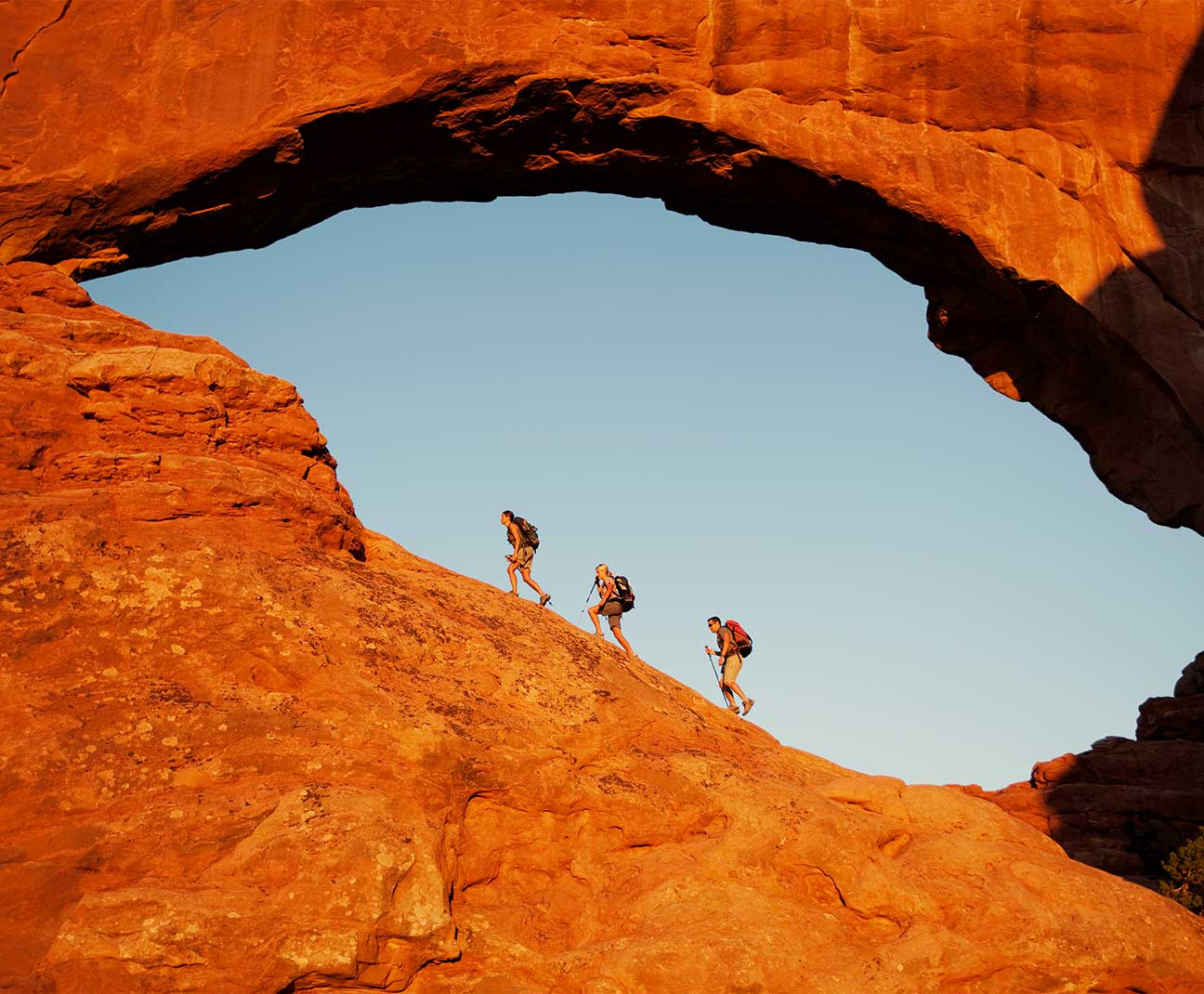 hikers climbing red rock hill