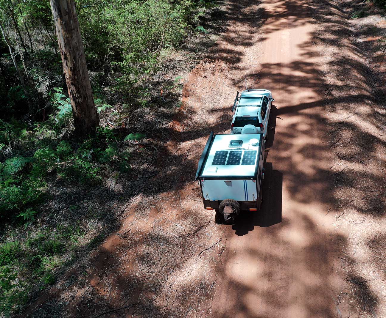 truck with trailer driving on a dirt road through the woods