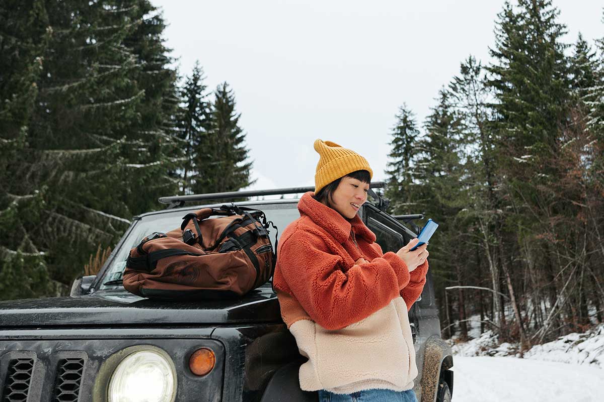 Woman using a smartphone by her car