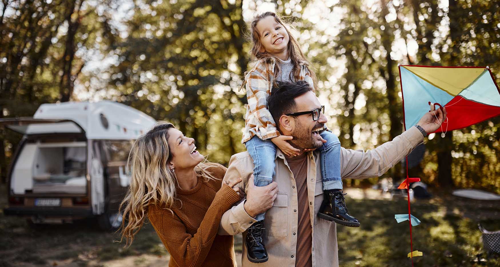 family with a motorhome playing with a kite