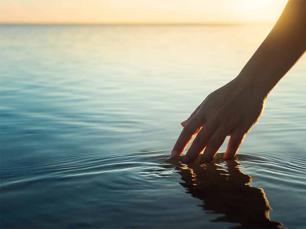 hand touching a glassy lake