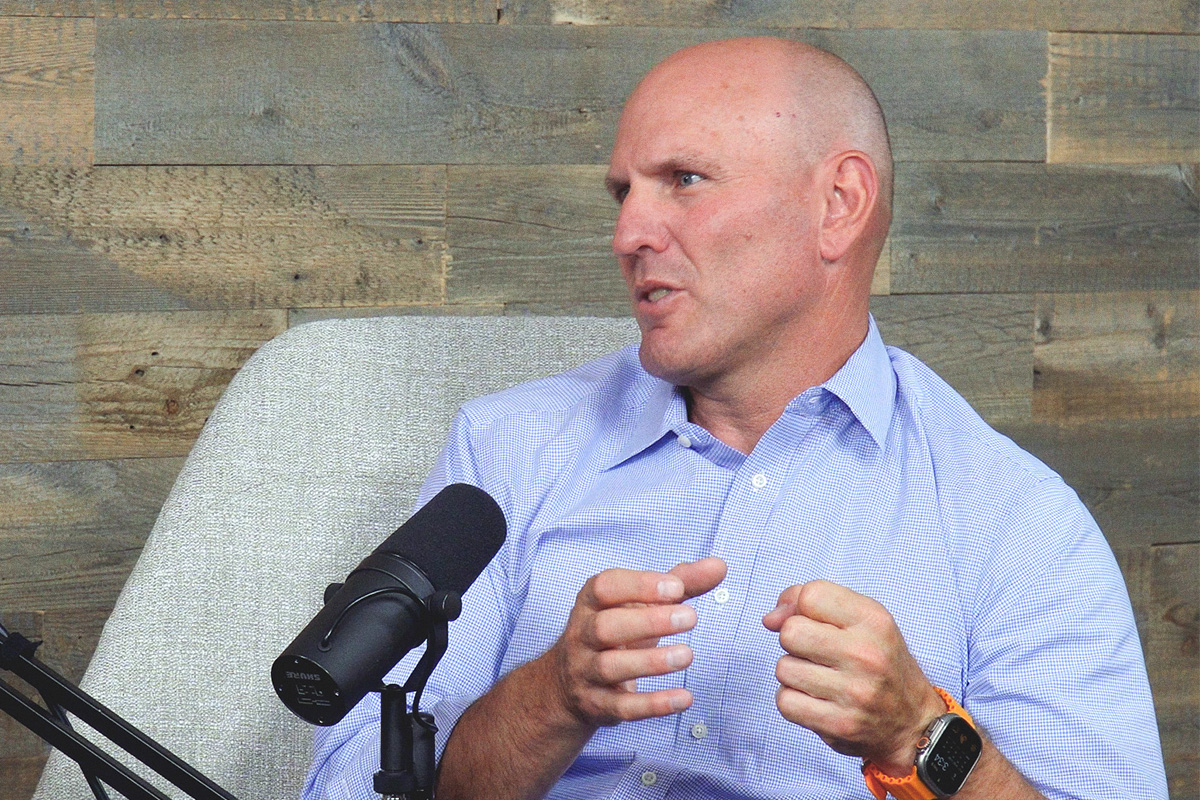 bald man in blue shirt sitting at the podcast mic