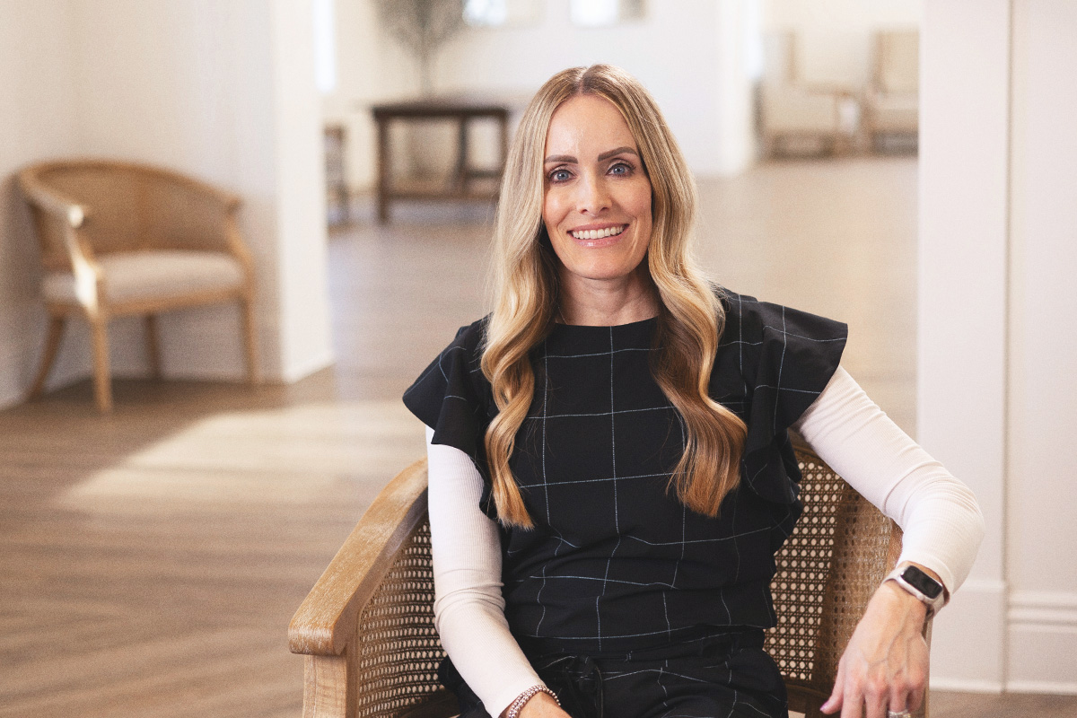 Blonde woman with black and white top sitting in chair