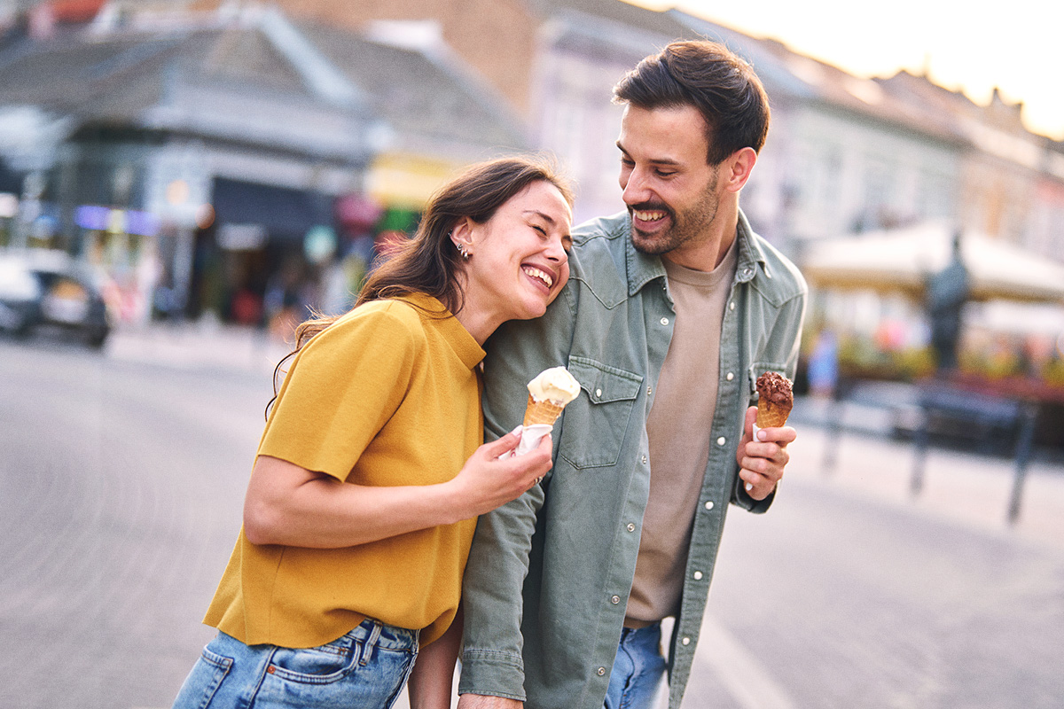 male and female couple walking arm in arm with ice cream