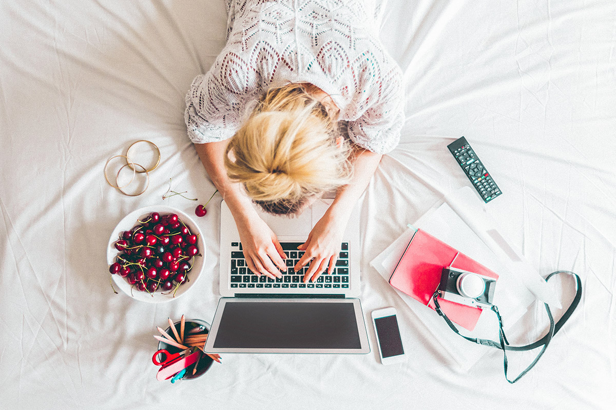 woman working on her laptop on her bed