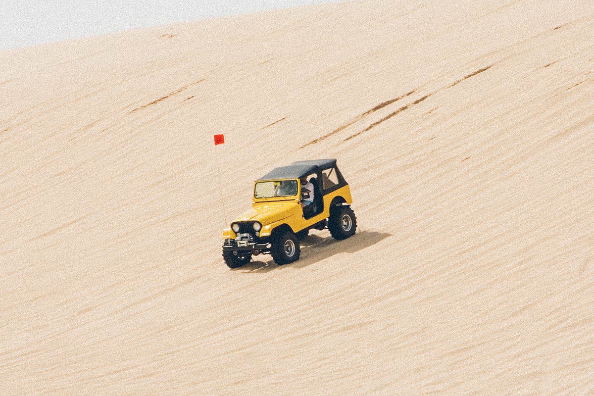 yellow 4-wheel drive car driving on sand dunes