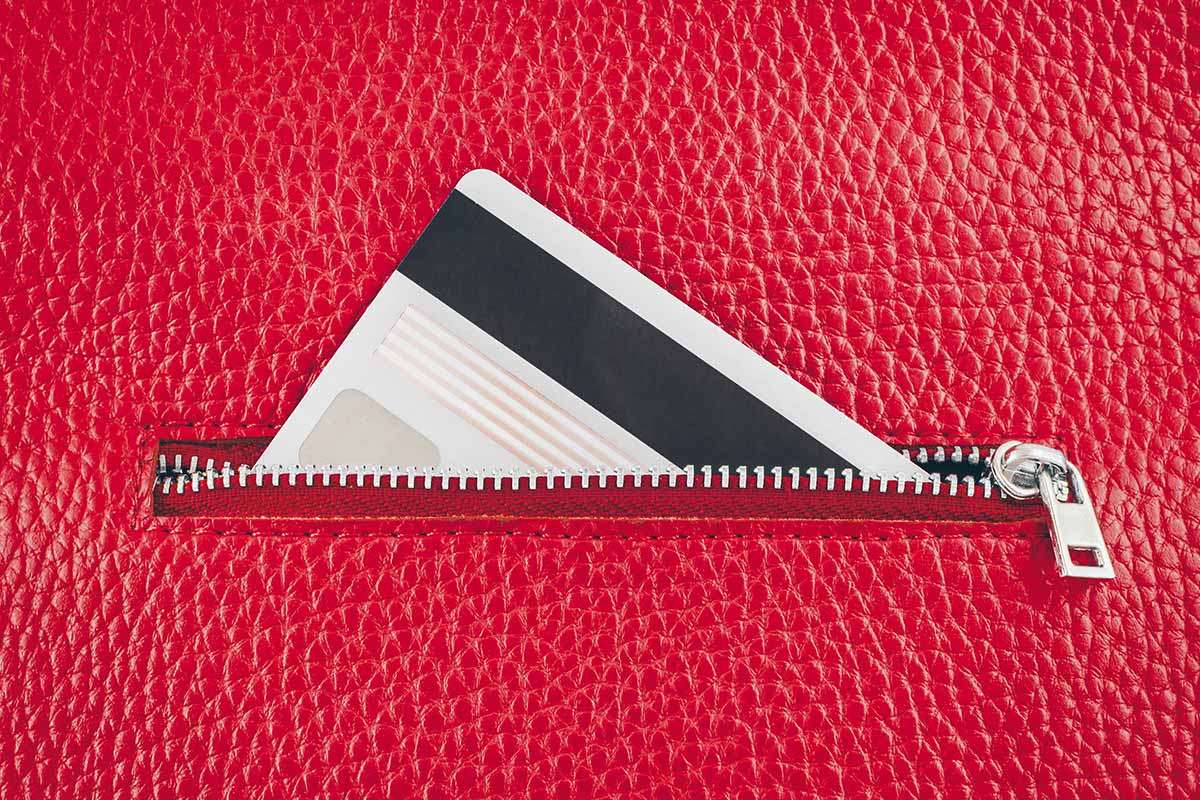 a zipper pocket on a red wallet with a card peeking out