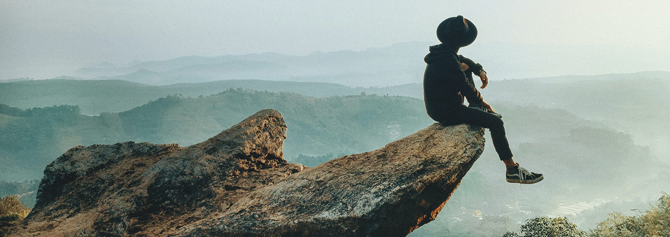 man sitting on rocky bluff