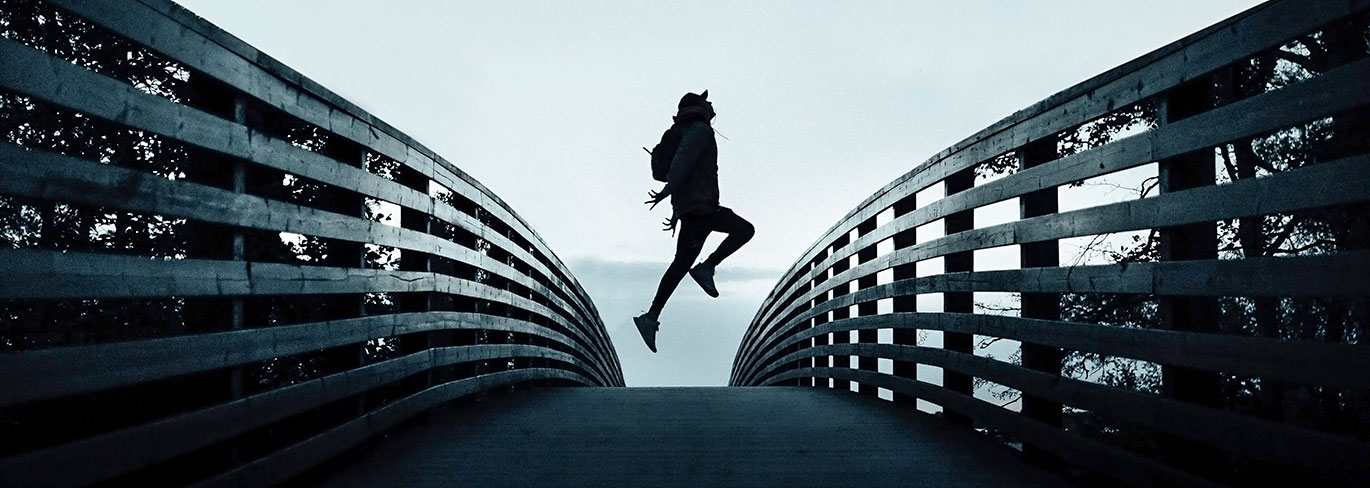 man jumping on bridge