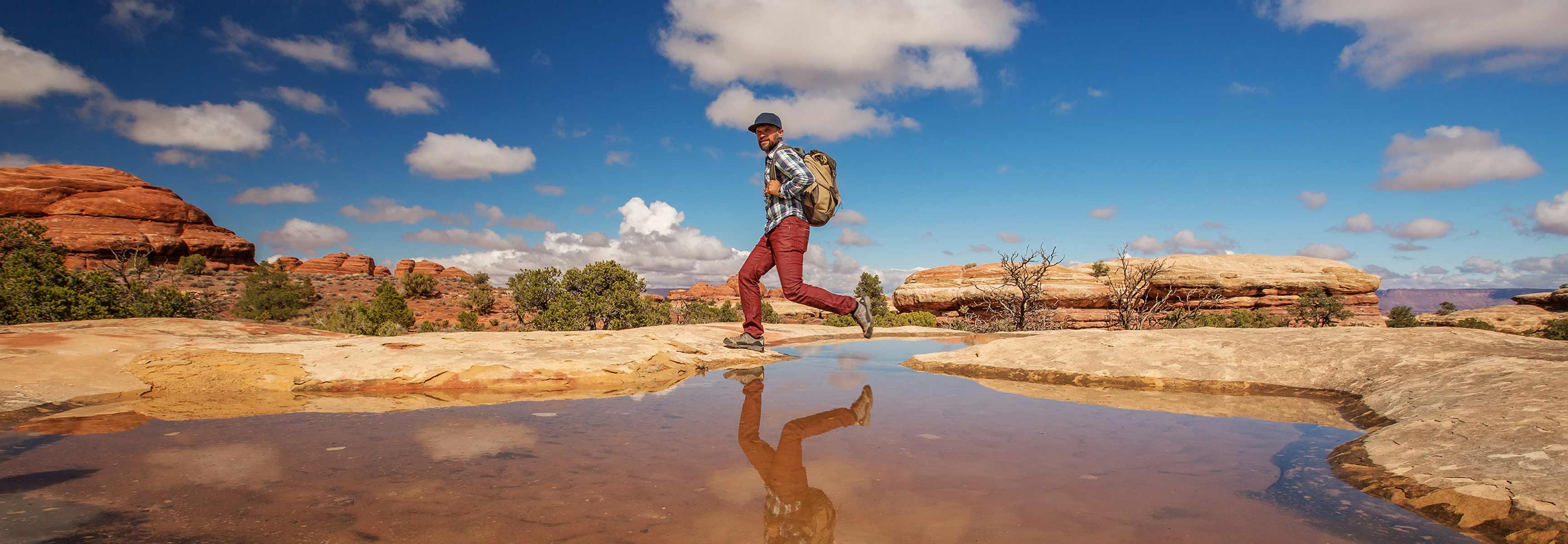 Hiker jumping over a stream