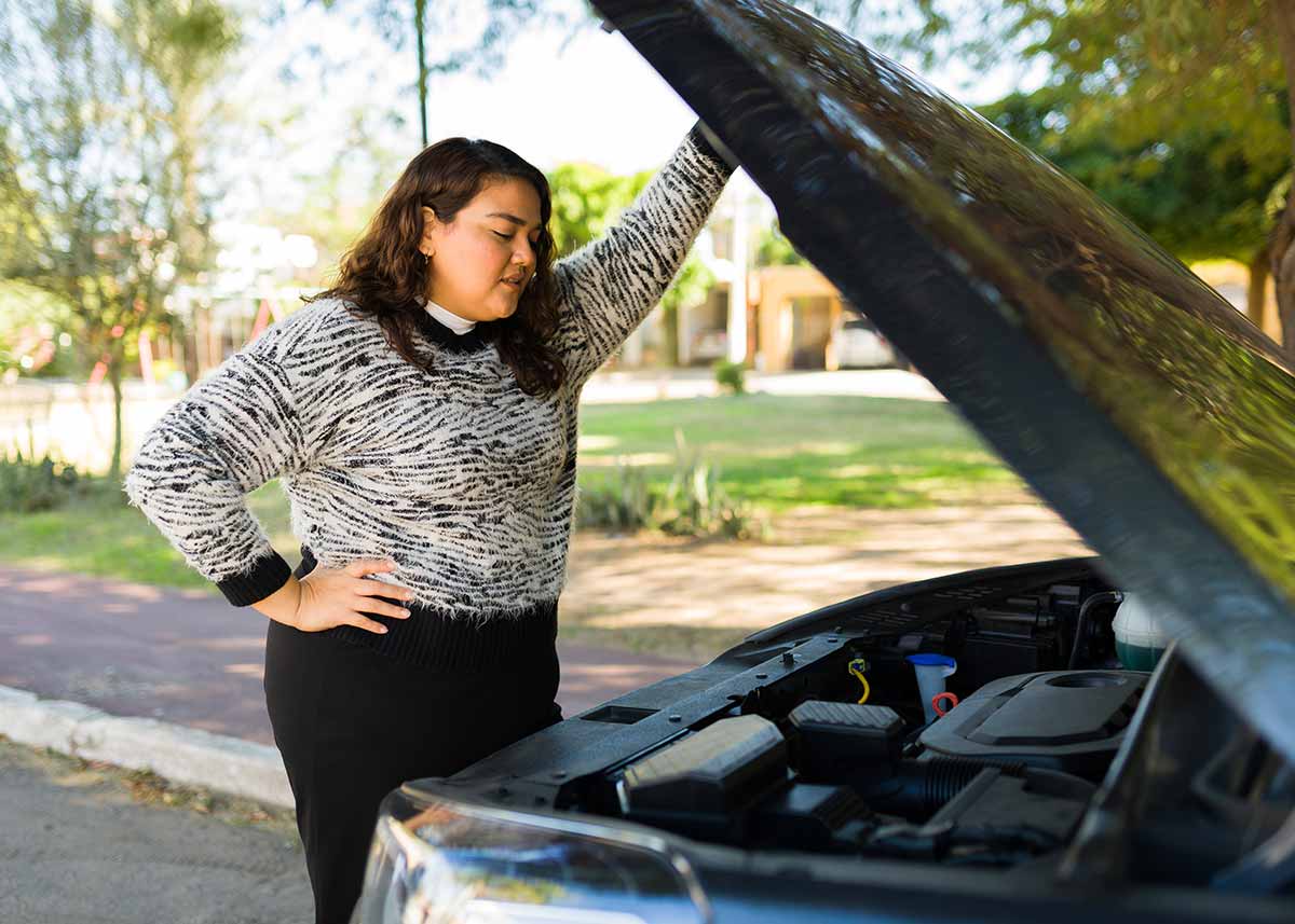 Woman checking the motor on broken car