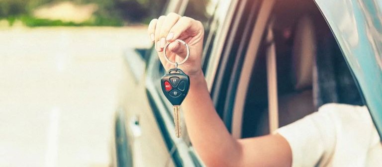 Person holding car keys out of car window