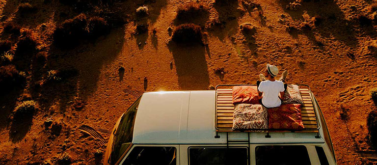 man sitting on top of his van in the desert