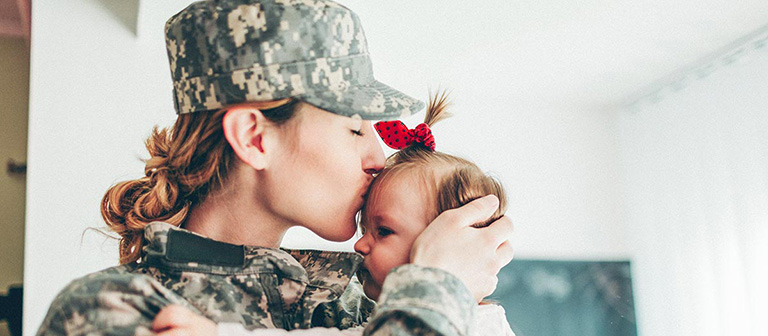 military woman kissing her baby on the forehead