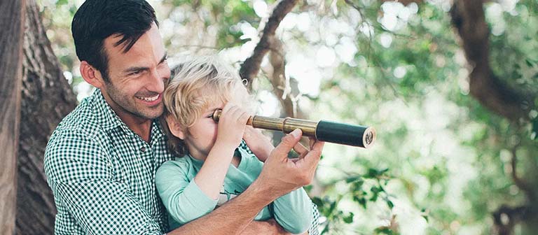 father and son looking through a telescope in a tree