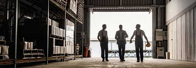 Silhouette of three men in a warehouse